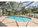 Sparkling blue pool surrounded by brick patio, lush landscaping, and a screened enclosure at 5109 Hartwell Loop, Land O Lakes, FL 34638