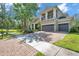 Long brick paved driveway leading up to a tan two-story home with a balcony and three-car garage at 5117 Longspur Ct, Lithia, FL 33547