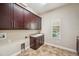 Functional laundry room featuring custom cabinets, a utility sink, and a window for natural light at 5117 Longspur Ct, Lithia, FL 33547