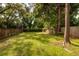 A spacious and grassy backyard surrounded by a wooden fence and mature trees, creating a private and natural setting at 5527 Kelly N Dr, St Petersburg, FL 33703