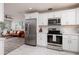 Bright kitchen with stainless steel appliances, white cabinetry, and open access to the living room at 5527 Kelly N Dr, St Petersburg, FL 33703