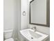 Modern half bathroom with a sleek sink, toilet, and decorative mirror at 6605 N Nebraska Ave # 25, Tampa, FL 33604