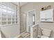 Bathroom featuring a tiled shower, glass block window, toilet, and access to the ensuite bedroom at 6805 Arroyo Dr, New Port Richey, FL 34652