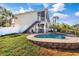 Exterior view of the home featuring a pool, lush landscaping, and a second-story deck at 6805 Arroyo Dr, New Port Richey, FL 34652
