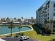 Exterior of condo building with water view, palm trees, parking and grassy areas under a clear blue sky at 7910 Sun Island S Dr # 404, South Pasadena, FL 33707