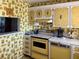 Retro kitchen with yellow cabinets, appliances, and wallpaper at 7910 Sun Island S Dr # 404, South Pasadena, FL 33707