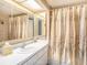 Cozy bathroom features a vanity with mirror, shower with floral curtain, and neutral decor at 830 S Gulfview Blvd # 102, Clearwater Beach, FL 33767