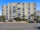 Multi-story condo building featuring balconies, lush landscaping, and convenient parking at 830 S Gulfview Blvd # 102, Clearwater Beach, FL 33767