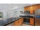 Well-lit kitchen featuring granite countertops, stainless steel appliances, and wooden cabinets at 9050 Lake Place Ln, Tampa, FL 33634
