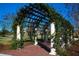 Picturesque arbor adorned with climbing vines and a brick walkway at 9443 Raised Tulip Ln, Land O Lakes, FL 34637