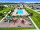Aerial view of a community pool with a playground surrounded by lush landscaping and walking paths at 1009 Wynnmere Walk Ave, Ruskin, FL 33570