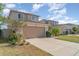 View of a two-story home with a two car garage, well-kept landscaping, and healthy green grass in a residential area at 10424 Laguna Plains Dr, Riverview, FL 33578
