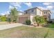 View of a two-story home with a two-car garage, a landscaped front yard with a palm tree, and healthy green grass at 10424 Laguna Plains Dr, Riverview, FL 33578