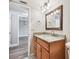 Bathroom vanity has granite counters, framed mirror, decorative lighting, and laminate floors into the next room at 13618 Greenfield Dr # 105, Tampa, FL 33618
