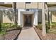 Covered entrance to condo building #13618 is framed by palm trees, with visible interior lighting at 13618 Greenfield Dr # 105, Tampa, FL 33618