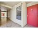 Condo hallway featuring a bright red door, window with blinds, and tiled floor at 13618 Greenfield Dr # 105, Tampa, FL 33618