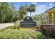 Community signage surrounded by mature palm trees and lush landscaping under a sunny sky at 13618 Greenfield Dr # 105, Tampa, FL 33618