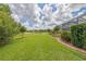 Expansive backyard with lush green grass, manicured landscaping, a serene pond and screened in pool at 16712 Courtyard Loop, Land O Lakes, FL 34638