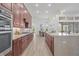 Long kitchen design with granite countertops, dark wood cabinets, and stainless steel appliances creates a functional flow at 16712 Courtyard Loop, Land O Lakes, FL 34638