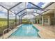 Screened-in pool with blue water, stone decking, and views of a lush green treeline at 16712 Courtyard Loop, Land O Lakes, FL 34638