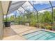 Screened-in pool with blue water, stone decking, and views of lush greenery and trees at 16712 Courtyard Loop, Land O Lakes, FL 34638