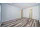 Bright, empty bedroom with wood-look floors, white walls, and two doorways providing access to other parts of the home at 1799 N Highland Ave # 106, Clearwater, FL 33755
