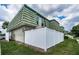 Condo exterior with green roof, white fence, well-maintained lawn, and mature landscaping at 1799 N Highland Ave # 106, Clearwater, FL 33755