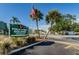 Fountain Square Condominium signage with palm trees, greenery, American flag, and street view showcasing a well-maintained entrance at 1799 N Highland Ave # 106, Clearwater, FL 33755