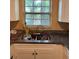 Kitchen sink area with dark countertops, white cabinets, and a window providing natural light at 1806 Marvy Ave, Tampa, FL 33612