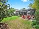 Inviting backyard featuring a screened-in porch, stone firepit, manicured lawn, and lush landscaping, perfect for outdoor entertaining at 2621 Stearns Rd, Valrico, FL 33596