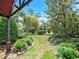 Landscaped backyard featuring a stone path, lush plants, and mature trees at 2621 Stearns Rd, Valrico, FL 33596