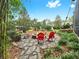 Cozy backyard firepit area with chairs, set in a stone patio surrounded by lush landscaping and mature trees at 2621 Stearns Rd, Valrico, FL 33596