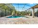 Relaxing screened-in pool area featuring stone flooring and a view of the landscaped backyard at 2621 Stearns Rd, Valrico, FL 33596