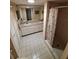 Bright bathroom featuring a double sink vanity, white tiled floors, and a shower with a shell curtain at 3835 Sailmaker Ln # X, Holiday, FL 34691