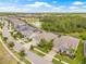 Aerial view of a residential neighborhood with homes, streets, a pond, and lush green trees in the background at 4166 Epic Cv, Land O Lakes, FL 34638