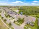 Aerial view of a residential neighborhood with homes, streets, a pond, and lush green trees in the background at 4166 Epic Cv, Land O Lakes, FL 34638