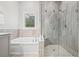 Bright bathroom features a soaking tub and glass enclosed shower with bench and tiled walls at 4166 Epic Cv, Land O Lakes, FL 34638