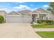 Charming one-story home featuring a three-car garage and beautifully landscaped front yard with colorful flowers at 4166 Epic Cv, Land O Lakes, FL 34638