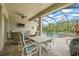 Covered lanai with travertine pavers, dining area, ceiling fan, TV and outdoor furniture at 4166 Epic Cv, Land O Lakes, FL 34638