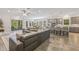 Spacious open-concept living room with a large gray sofa, kitchen bar seating, and access to the outdoor patio at 4166 Epic Cv, Land O Lakes, FL 34638