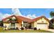 Charming yellow home featuring a red tile roof, well-manicured lawn, tropical landscaping, and an attached two-car garage at 5001 Queen Palm Ne Ter, St Petersburg, FL 33703