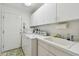 Efficient laundry room with white cabinets, sink, and appliances, adjacent to a door at 5001 Queen Palm Ne Ter, St Petersburg, FL 33703