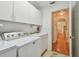 Bright laundry room with white cabinetry, washer, sink, and doorway leading to the rest of the home at 5001 Queen Palm Ne Ter, St Petersburg, FL 33703