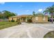 Beautiful tan home featuring a concrete circular driveway and well-maintained landscaping under a blue sky at 534 Berkley Ave, Tarpon Springs, FL 34689