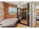 Bathroom showcasing soaking tub, glass shower enclosure, tile floors, and a wood accent wall at 5817 Myrtle Ln, Tampa, FL 33625