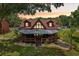 Charming cabin-style home with a wraparound porch, manicured lawn, and serene pond, highlighting curb appeal at 5817 Myrtle Ln, Tampa, FL 33625