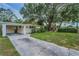 Charming single-story home with a covered carport and a lush front yard with mature trees in the background at 629 Lexington St, Dunedin, FL 34698
