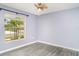 Bedroom with gray vinyl flooring and a ceiling fan; view of front yard through the window at 7305 Tiger Trail Ct, Sun City Center, FL 33573