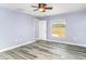 A bright, airy bedroom featuring gray vinyl flooring, a ceiling fan and a window overlooking the fenced backyard at 7305 Tiger Trail Ct, Sun City Center, FL 33573