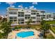 An exterior view of a condo building with a swimming pool, lounge chairs, and palm trees at 7872 Sailboat Key S Blvd # 301, South Pasadena, FL 33707